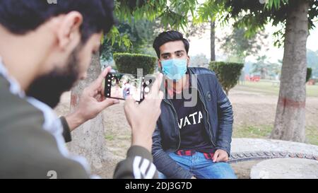 person taking photo of his friend wearing face mask Stock Photo