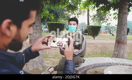 person taking photo of his friend wearing face mask Stock Photo