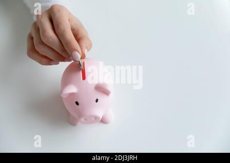 Top view close up woman putting coin in piggy bank Stock Photo