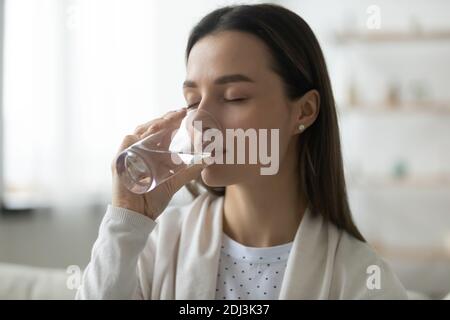 Calm beautiful young woman drinking fresh mineral water close up Stock Photo