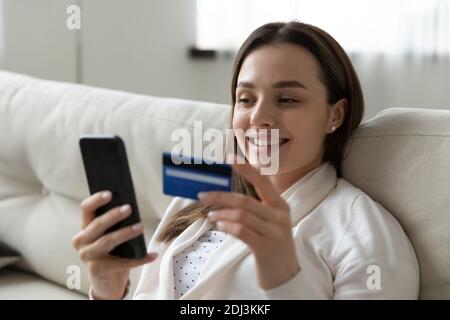 Close up smiling woman using phone, paying by credit card Stock Photo
