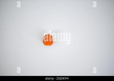One cherry tomato isolated on a white table Stock Photo