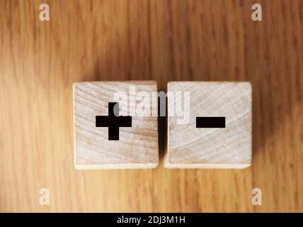 Plus and minus signs on wooden cubes on wooden table. Business solution concept. Stock Photo