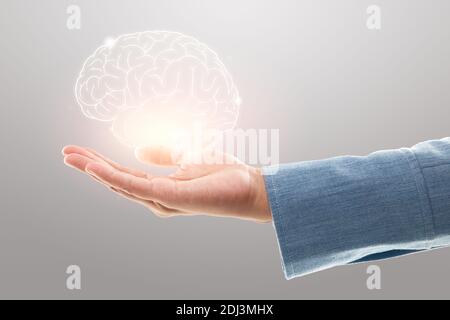 Female doctor holding brain illustration against the gray background. Mental health protection and care. Stock Photo