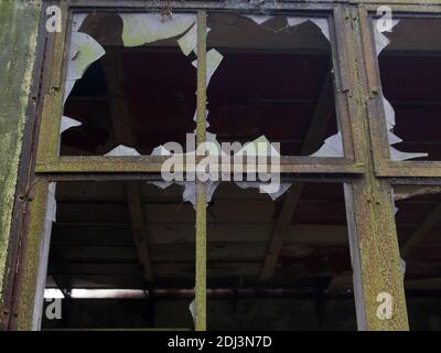 Broken windows with jagged glass in derelict old abandoned building  Stock Photo