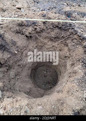 Drill auger digged round deep hole in clay for concrete casting of new house base. Ground and dirt Stock Photo