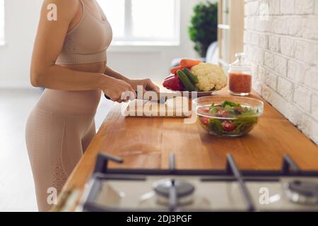 Unrecognizable fit woman standing at countertop and chopping vegetables for healthy salad Stock Photo