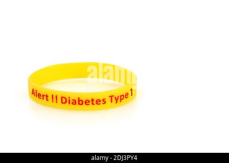 Diabetes type 1 alert wristband in yellow rubber silicone with red type on white background. Stock Photo