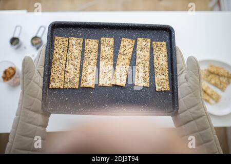 Gloved hands holding a black tray of Swedish crispbread Stock Photo