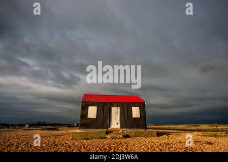Rye Harbour, December 12th 2020: Storm clouds gather over the iconic red roofed hut that sits on the shingle beach at the entrance to Rye Harbour Credit: Andrew Hasson/Alamy Live News Stock Photo