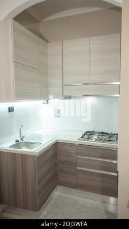 View of a modular corner kitchen in gray and brown color, the led under-cabinet light attracts attention. Stock Photo