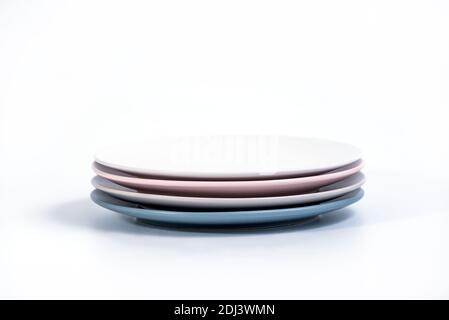 Stack of four colorful empty plates isolated on white background, side view. Navy Blue, Grey, Pink and White empty plates collection Stock Photo