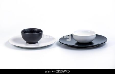Black and White Bowls in White and Black Plates isolated on white background, side view. Stock Photo