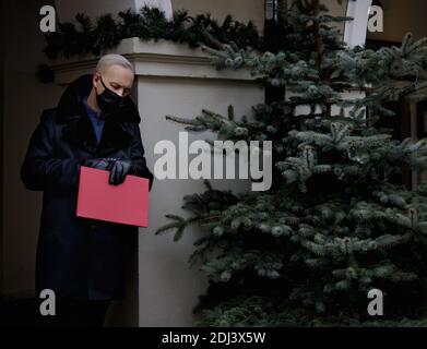man in a black coat holds a red folder in his hands and watches the clock.  Stock Photo