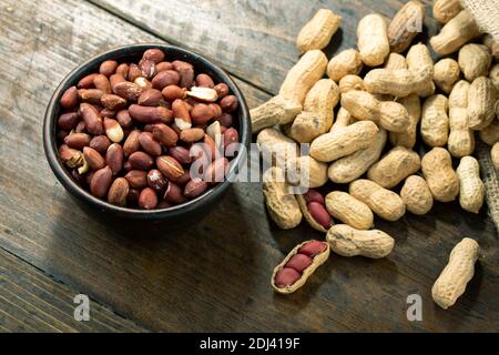 Peanuts in a clay plate on a wooden table. Inshell nuts. Selective focus Stock Photo