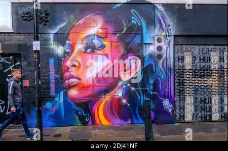 Man walks next to street art mural by Mr Cenz on Bacon Street & Brick Lane, Shoreditch, East London, England Stock Photo