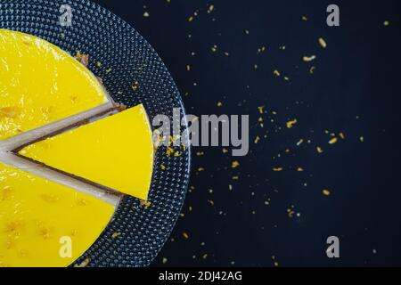 Sliced lemon cheesecake on glass plate at black background. Stock Photo