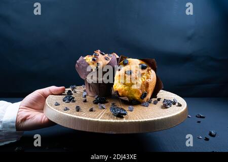 Woman holding chocolate and raisin muffin on plate Stock Photo