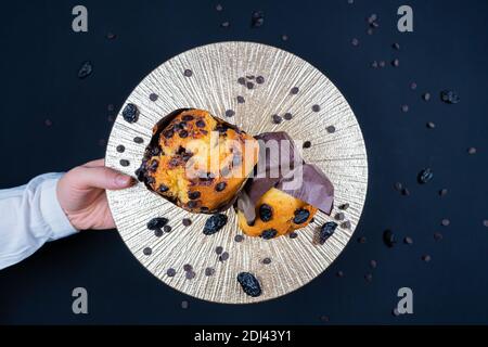 Woman holding chocolate and raisin muffin on plate Stock Photo
