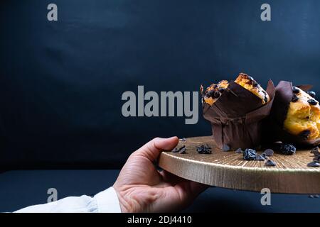 Woman holding chocolate and raisin muffin on plate Stock Photo