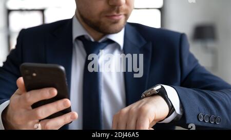 Close up confident businessman holding smartphone, checking time, planning Stock Photo