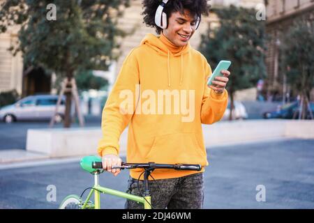 Young millennial biker listening playlist music app with mobile phone app in the city - Focus on face Stock Photo