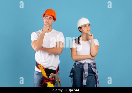 Renovation Planning . Portrait Of Pensive Young Couple In Protective Hard Hats Stock Photo