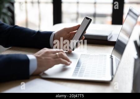 Close up businessman using phone and laptop, working online Stock Photo