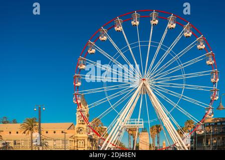 Adelaide, South Australia - January 12, 2019: Glenelg Giant Ferris Wheel at Moseley Square viewed from the jetty at sunset time Stock Photo