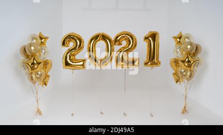 Golden balloons numbers date 2021 filled with helium and party balloons on the side on ribbon isolated on white background. Happy new year 2021 Stock Photo