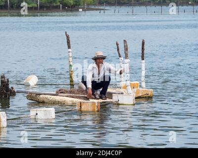 Fisherman tending to his nets from a raft made from polystyrene foam on Dinh River near Vung Tau in the Bang Ria-Vung Tau Province of South Vietnam. Stock Photo