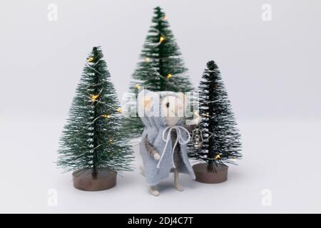 White little rat among beautiful holiday trees in the forest. A toy in the form of a plush rat Stock Photo
