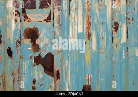 Old rusty metal painted with blue color. Empty blue wall texture background. Peeling paint on blue striped wall. Rust and oxidized metal. Stock Photo