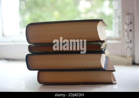 four books on white table near the window. Selective focus. Education concept. Stock Photo