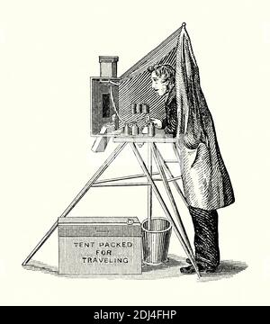 An old engraving of a photographer and his portable-darkroom tent studio in the 1800s. It is from a Victorian mechanical engineering book of the 1880s. Out in the field early photographers needed somewhere to process their photographic glass plates. Wheeled vehicles were sometimes used but at its most basic a tent could be set up on a tripod to enable the processing using the chemicals and water required. It had to be light-free, with ‘yellow glass’ allowing a degree of visibility within the canvas enclosure. All could be packed away in the box below the tripod. Stock Photo