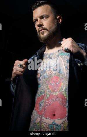Young handsome masculin man , in unfastened denim shirt with tattoo on his chest. Stock Photo