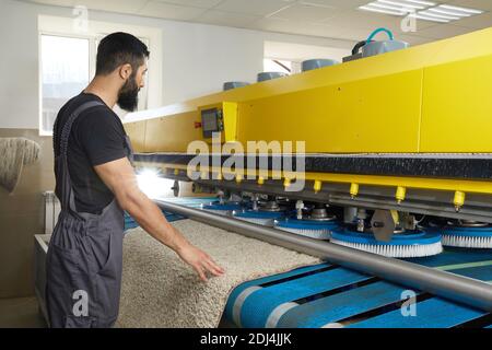 Man operating carpet automatic washing machine in professional laundry service Stock Photo