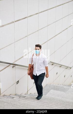 Man in mask walking up the stairs Stock Photo