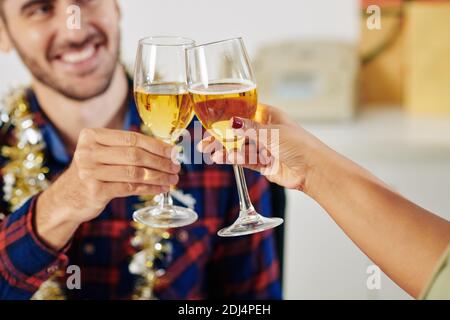 Close-up image of colleagues enjoying small Christmas celebration and toasting with chamagne glasses Stock Photo