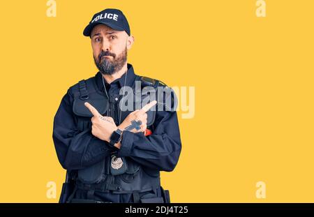 Young handsome man wearing police uniform pointing to both sides with fingers, different direction disagree Stock Photo