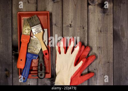 Set of various working painting tools - spatulas, brush, tray and work gloves on a dark wooden background with copy space. Stock Photo