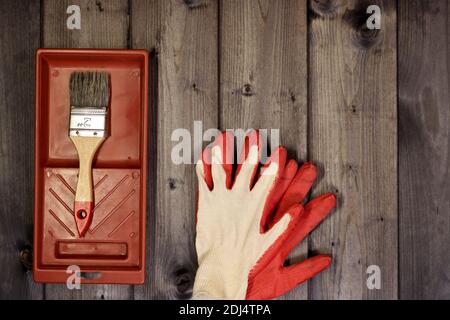 Set of working painting tools - brush, tray and work gloves on a dark wooden background with copy space. Stock Photo
