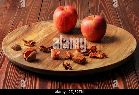 Ripe red apples and pieces of dried fruit on a large wooden platter Stock Photo