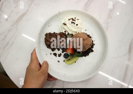 brownie , chocolate ice cream with whipping cream and fruit for serve Stock Photo