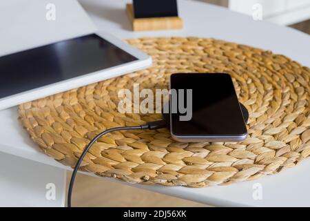 the phone lying on the wireless charger next to the tablet Stock Photo