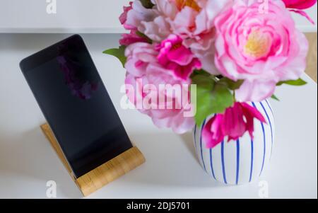 the telephone standing on the table in the apartment next to the vase of flowers Stock Photo