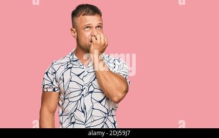 Handsome muscle man wearing casual clothes looking stressed and nervous with hands on mouth biting nails. anxiety problem. Stock Photo