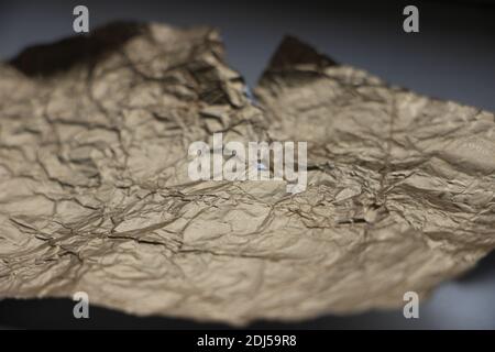 Crumpled and torn golden bronze shiny foil texture background. Stock Photo