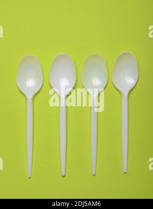 Plastic spoons for a picnic on a green background. Top view. Stock Photo