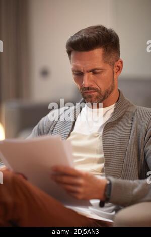 Vertical portrait of handsome mature businessman looking at documents while working from home Stock Photo